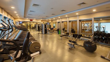 Ett gym med löpband, styrketräningsmaskiner och hantlar.