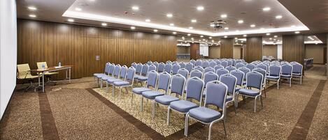 Ein Konferenzraum mit Stuhlreihen, Teppichboden und einer Holzwand.
