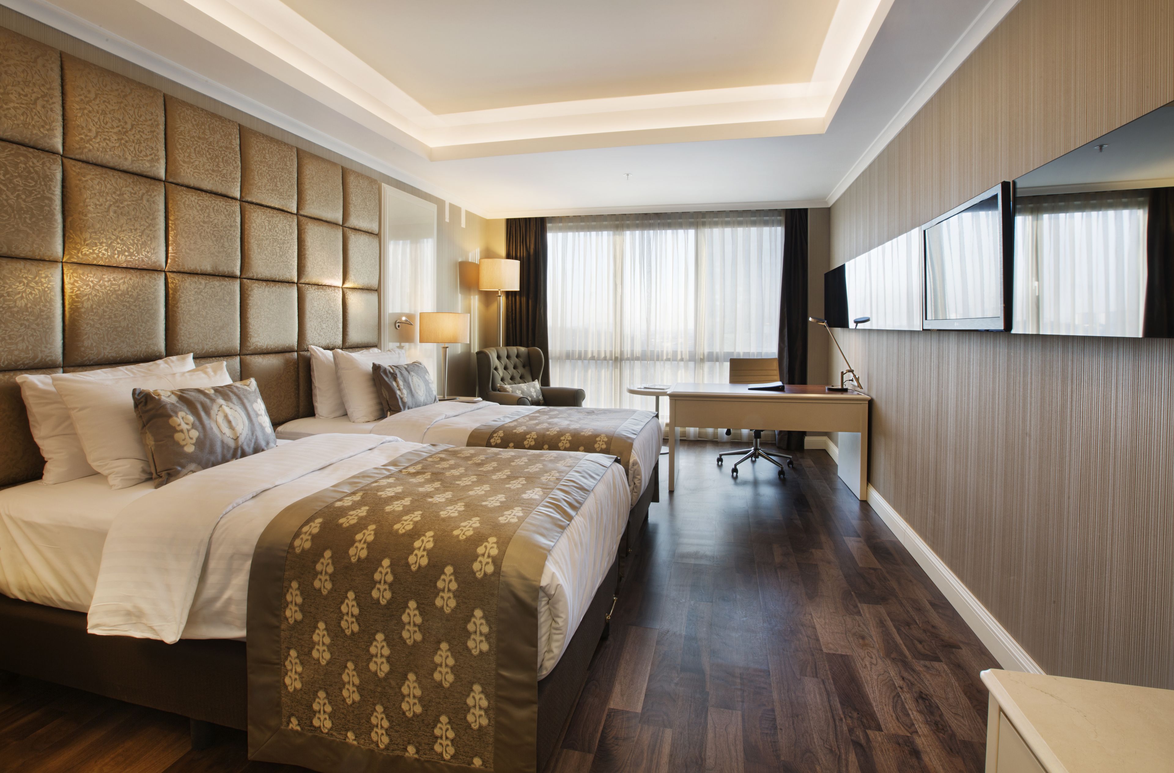 Una habitación de hotel con una cama grande, un escritorio, una silla y un televisor montado en la pared.