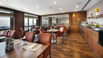 Un restaurante moderno con suelo de madera, mesas redondas y sillas color naranja.