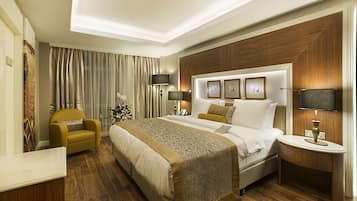 A hotel room with a large bed, a bedside table, a chair, and a nightstand.