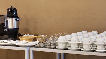 Un buffet avec des machines à café, des tasses blanches et de la verrerie.