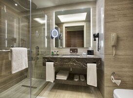 Un bagno moderno con cabina doccia in vetro, lavabo in marmo e uno specchio grande.