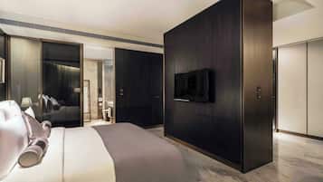 A modern hotel room with a large bed, a flat-screen TV mounted on the wall, and a wardrobe with a mirror.