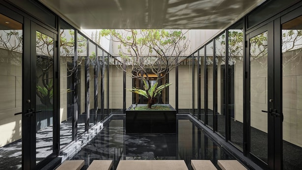 A modern building with glass doors and a central planter with a tree. - Madison Taipei, a Tribute Portfolio Hotel (Taipei)