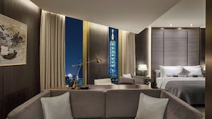 A modern hotel room with a large bed, a seating area with a sofa, a desk, and a view of a cityscape at night. - Madison Taipei, a Tribute Portfolio Hotel (Taipei)