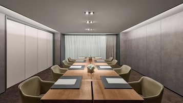 A conference room with a long table, chairs, and a plant centerpiece.