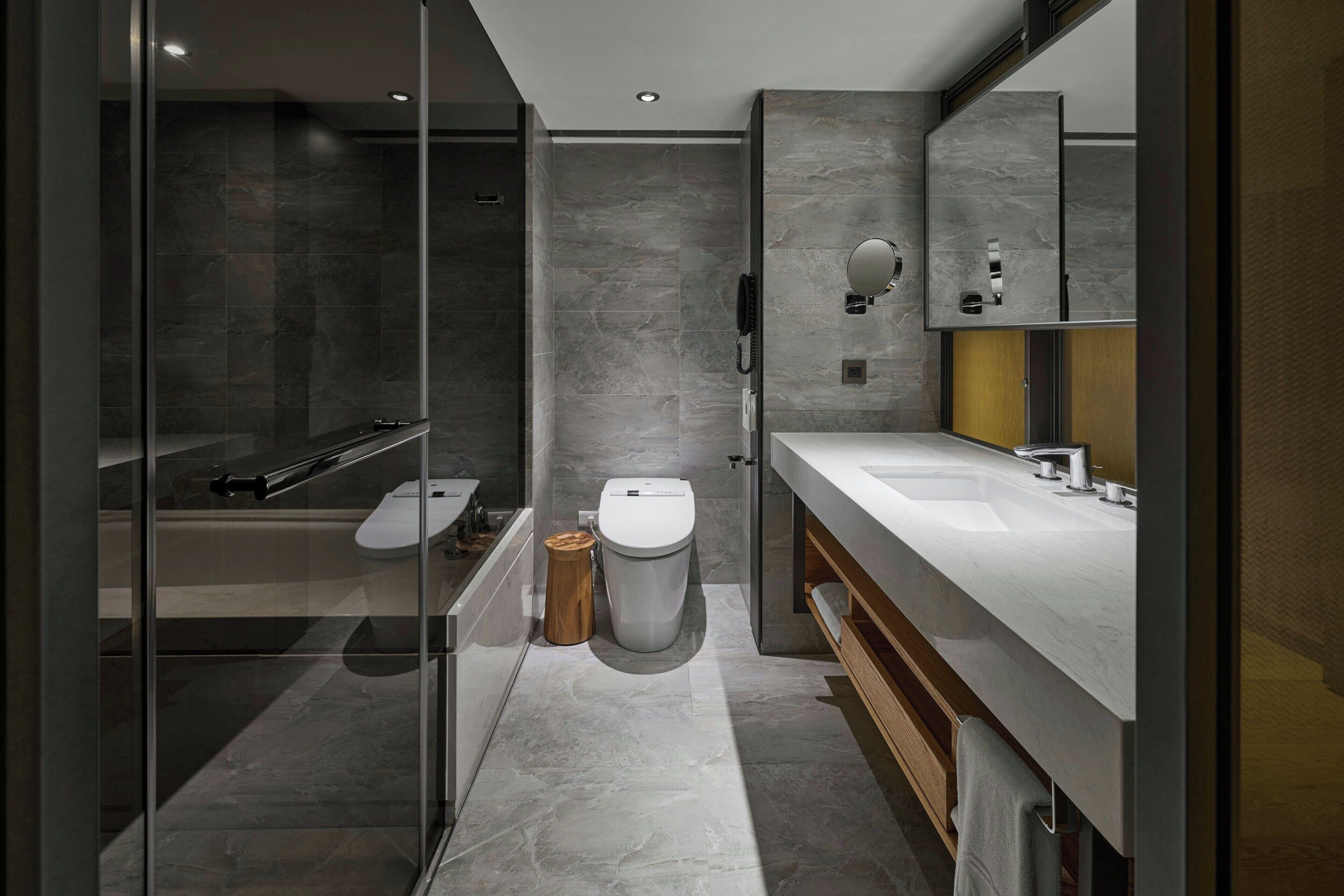 A modern bathroom with a glass shower enclosure, a toilet, and a vanity with a mirror.
