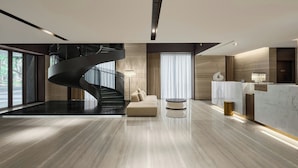 A modern hotel lobby with a marble floor, a spiral staircase, a reception desk, and a seating area. - Madison Taipei, a Tribute Portfolio Hotel (Taipei)