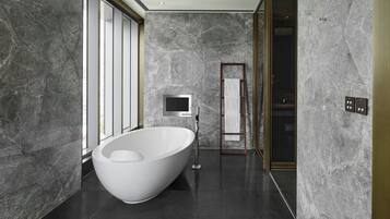 A modern bathroom with a freestanding bathtub, a large mirror, and a television.