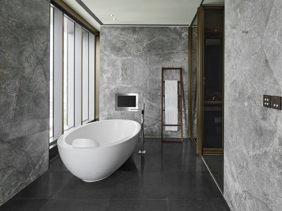 A modern bathroom with a freestanding bathtub, a large mirror, and a television.