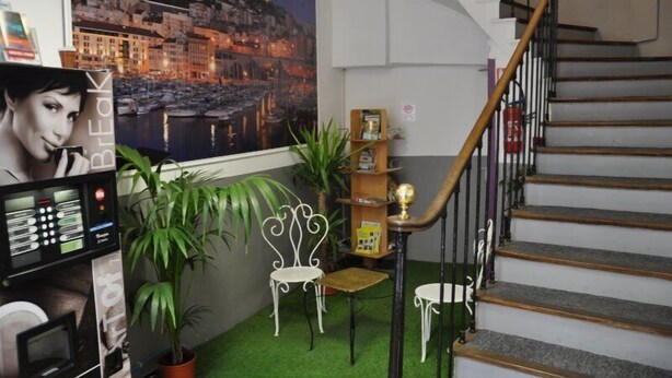 Ein Zimmer mit einer Treppe, einem Wandgemälde einer Küstenstadt, einem Schreibtisch mit einem Computer und zwei Stühlen.