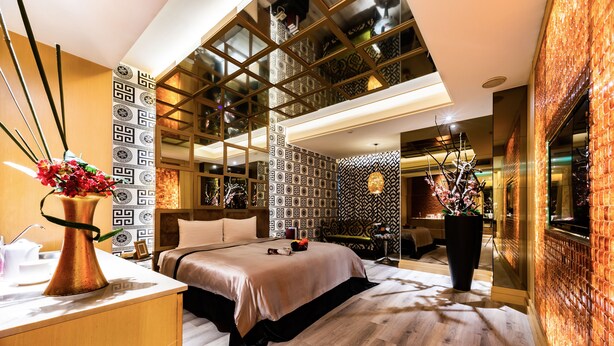 Una habitación de hotel moderna con una cama grande, un escritorio y un ventanal amplio.