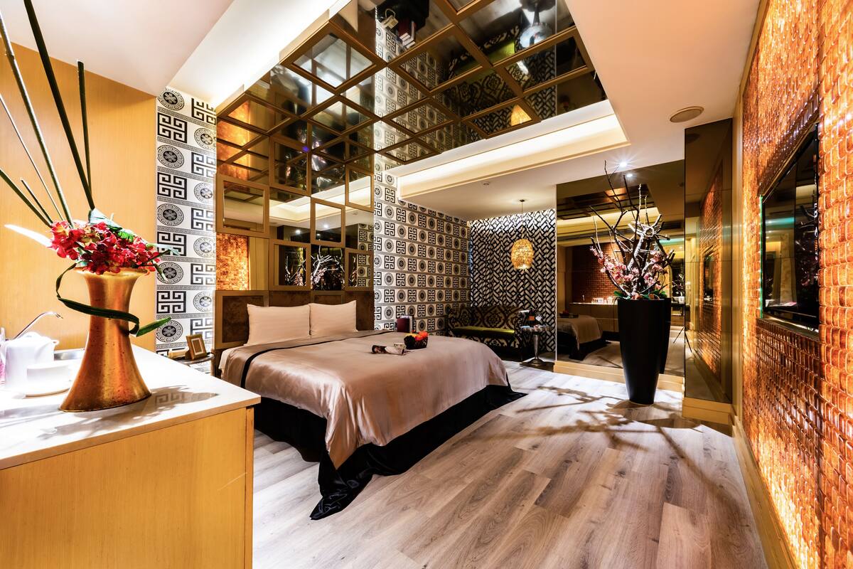Una habitación de hotel moderna con una cama grande, un escritorio y un ventanal amplio.