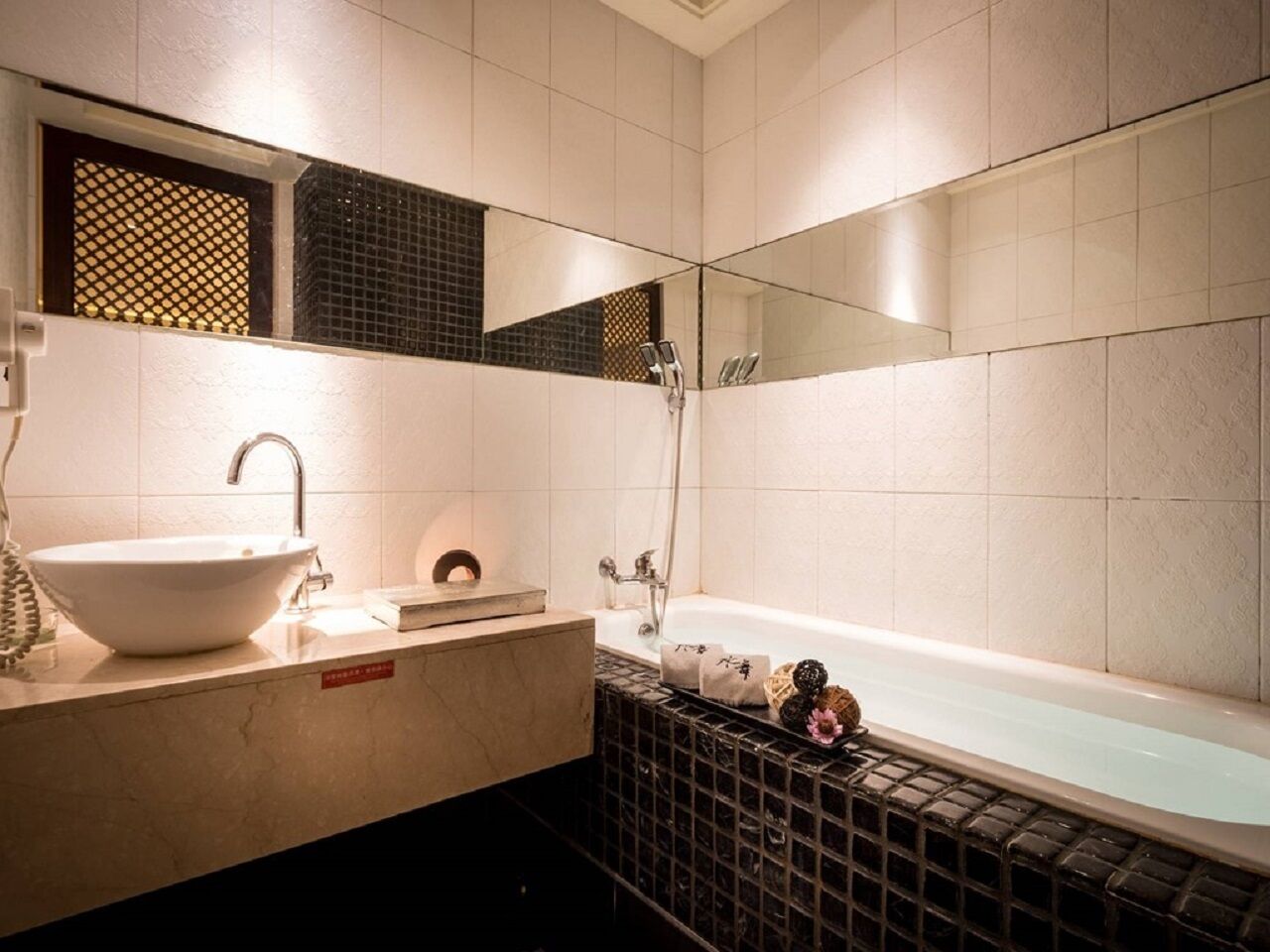 A bathroom with a white sink, a bathtub, and a mirror.