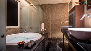 Un baño moderno con una bañera independiente, dos lavamanos y un espejo grande.