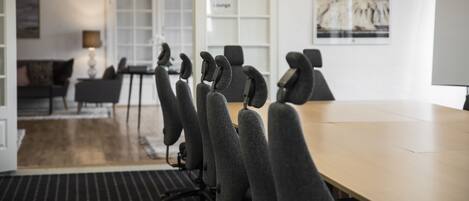 Un salón de conferencias con una larga mesa y filas de sillas.