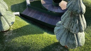 A miniature golf course with a green artificial turf, a circular putting area, and a small boat model in the background. - Rønnes Hotel (Fjerritslev)