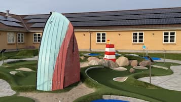 Play a round of golf amidst a scenic residential setting with obstacles like an arch, windmill, and pond.