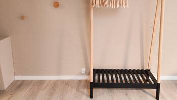Un tendedero de madera con pinzas y un estante negro, frente a una pared color beige con detalles de madera.
