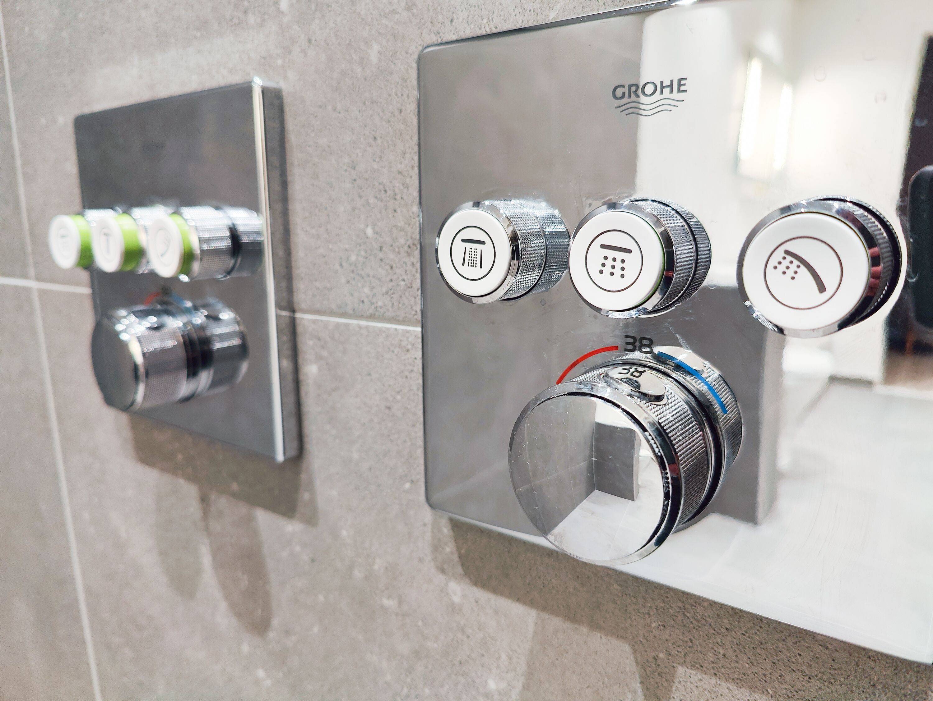 A modern bathroom with a GROHE shower control panel featuring multiple knobs and a digital display.