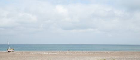 A beach with a small boat and a person in the distance.