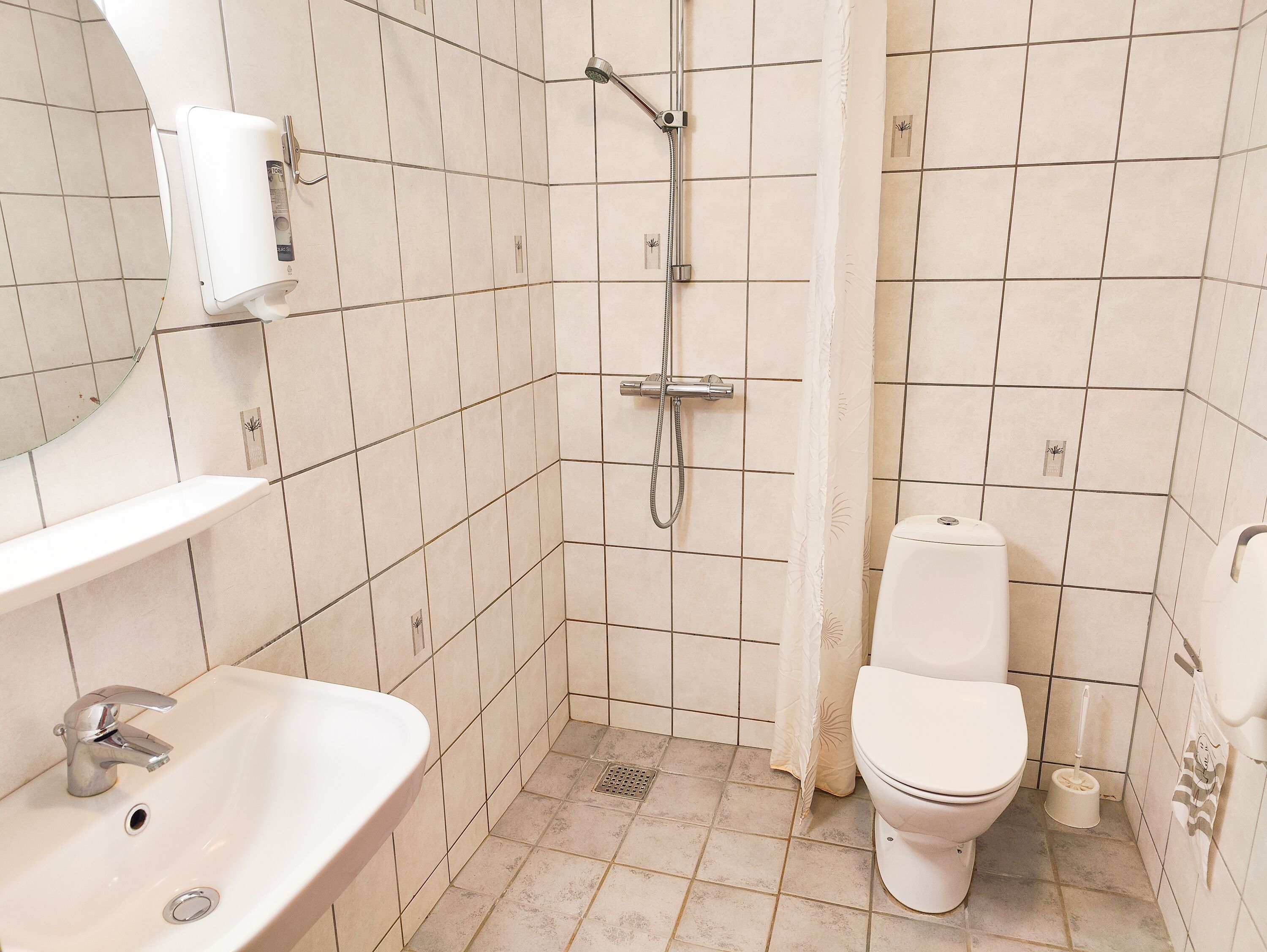 A bathroom with a sink, toilet, shower, and a towel rack.