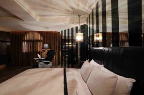 A hotel room with a large bed, a desk with a chair, a lamp, and two chandeliers. - Li Hsin Motel (Taichung)