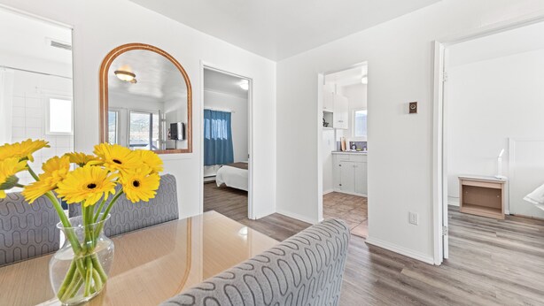 A modern hotel room with a dining area, a large mirror, and a view of the city. - 5000 Motel (Penticton)
