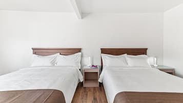Ein Hotelzimmer mit zwei Betten, einem Nachttisch mit Lampe und einem kleinen Tisch mit Blumenvase.
