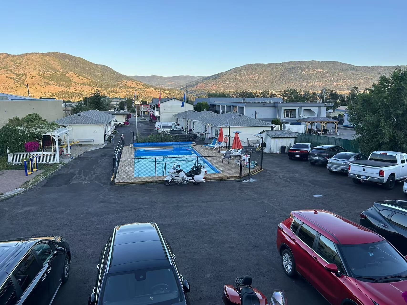 Un estacionamiento con piscina, rodeado de edificios y colinas.