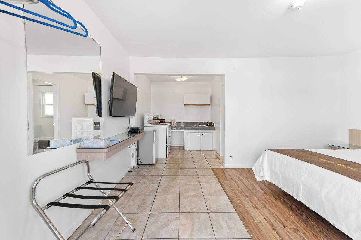 Una camera d'albergo con un letto, un angolo cottura, un bagno e una TV a parete.