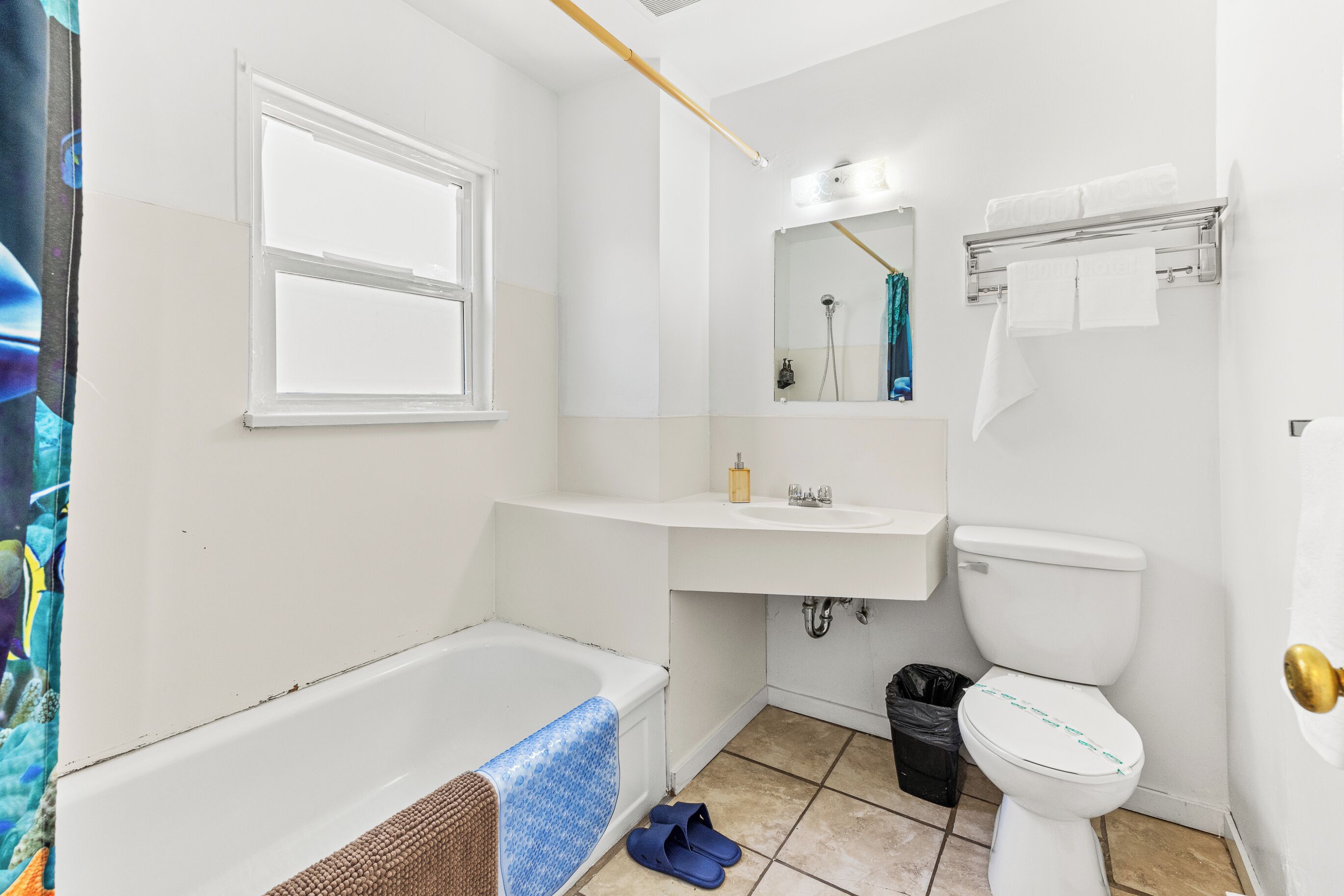 Ein Badezimmer mit Badewanne, Toilette, Waschbecken und einem Fenster.