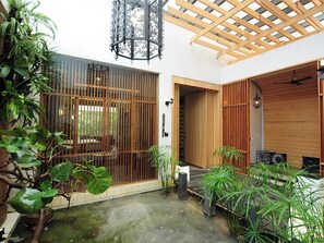 Un interior tradicional japonés con suelo de tatami, una puerta de madera y un techo con entramado de madera.