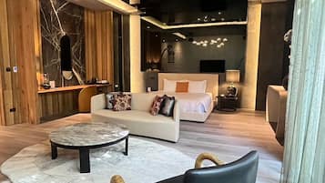 Une chambre d’hôtel moderne avec un lit, un canapé et une table basse ronde.