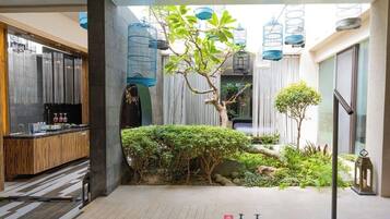 A modern interior space with a kitchen area, a seating area with a view, and a small garden with plants and a tree.