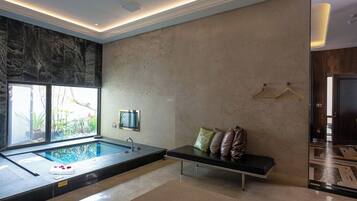 Un bagno moderno con una vasca da bagno ampia, una panca con cuscini e una finestra che lascia entrare luce naturale.