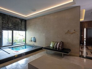 A modern bathroom with a large bathtub, a bench with cushions, and a window providing natural light. - Mulan Boutique Hotel - Taichung Branch (Taichung)