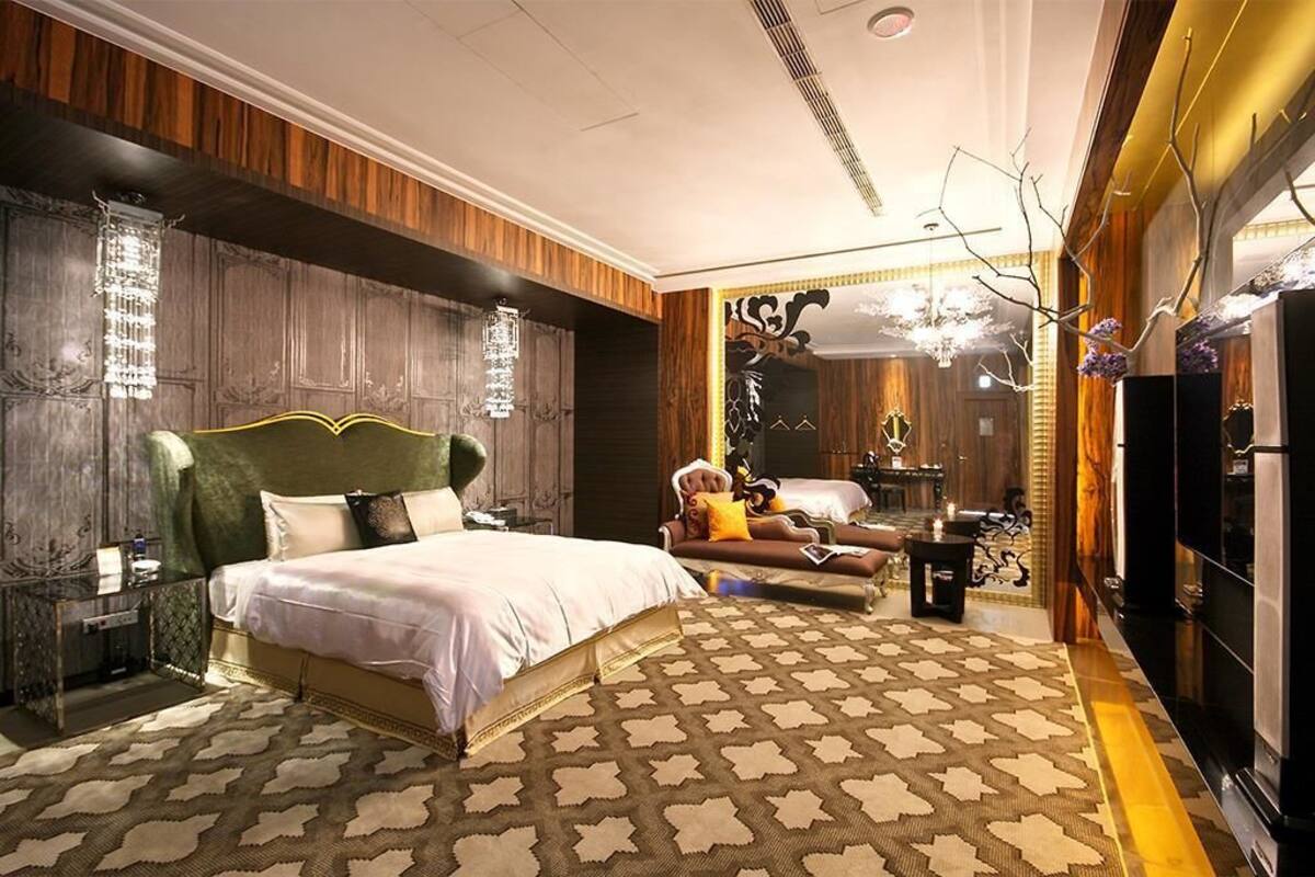 A spacious bedroom with a large bed, a vanity with a mirror, and a chandelier.