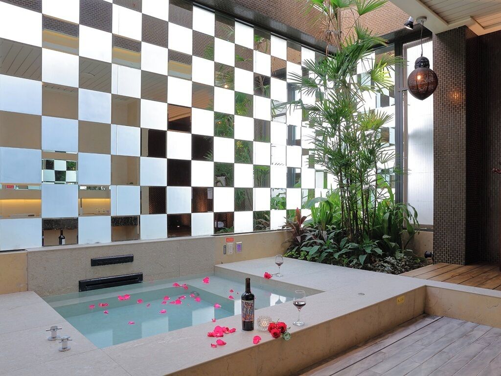 Un espace de détente avec un mur à motifs à carreaux, un jacuzzi et une plante en pot.