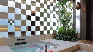 Un espace de détente avec un mur à motifs à carreaux, un jacuzzi et une plante en pot.