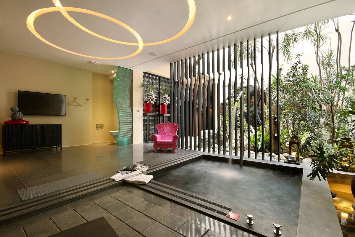 A modern interior with a large water feature, a flat-screen TV, and a seating area with a pink chair.