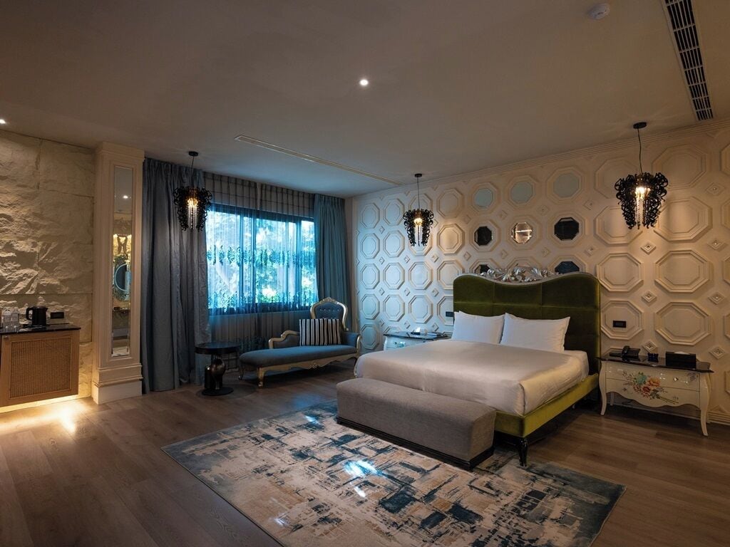 Un dormitorio moderno con una cama grande, un sofá y una ventana con cortinas.