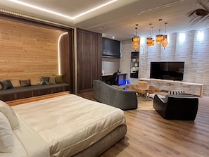 A modern living room with a large bed, seating area, and a TV. - Mulan Boutique Hotel - Taichung Branch (Taichung)
