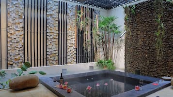 A spa area with a stone wall, a water feature, and plants.
