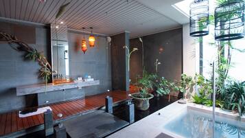 Un moderno espacio de spa con terraza de madera, un jacuzzi y varias plantas.