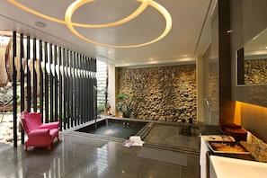 A modern spa area with a hot tub, a pink chair, and a stone wall. - Mulan Boutique Hotel - Taichung Branch (Taichung)