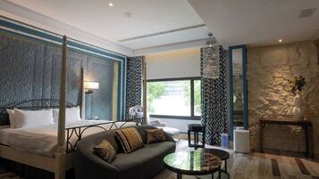Een moderne hotelkamer met een hemelbed, een bank, een ronde salontafel en een accentmuur van steen.