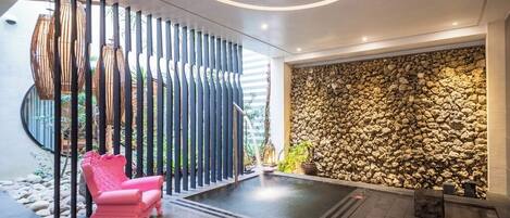 Um interior moderno com uma parede de pedra, uma cadeira rosa e um design de teto circular.