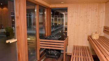 A sauna with wooden benches, a glass door, and a view of the outside.
